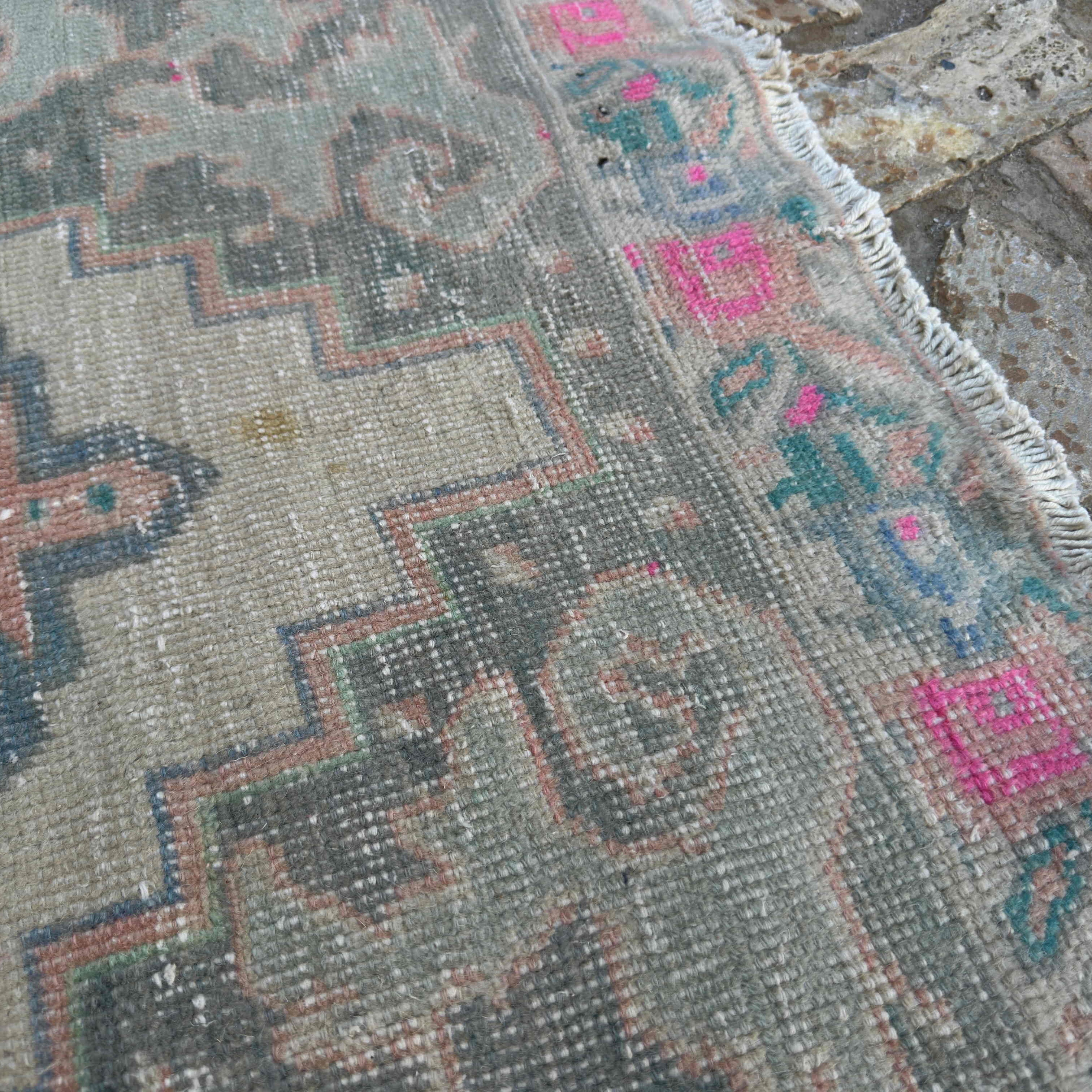 Close-up of the pink Turkish distressed rug showing traditional details, hand-knotted weave, wool and cotton and low pile.