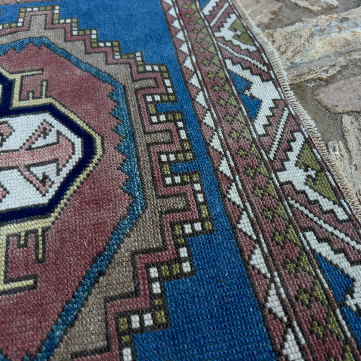 Close-up of the blue distressed turkish rug showing medallion details, hand-knotted weave, wool and cotton and low pile.