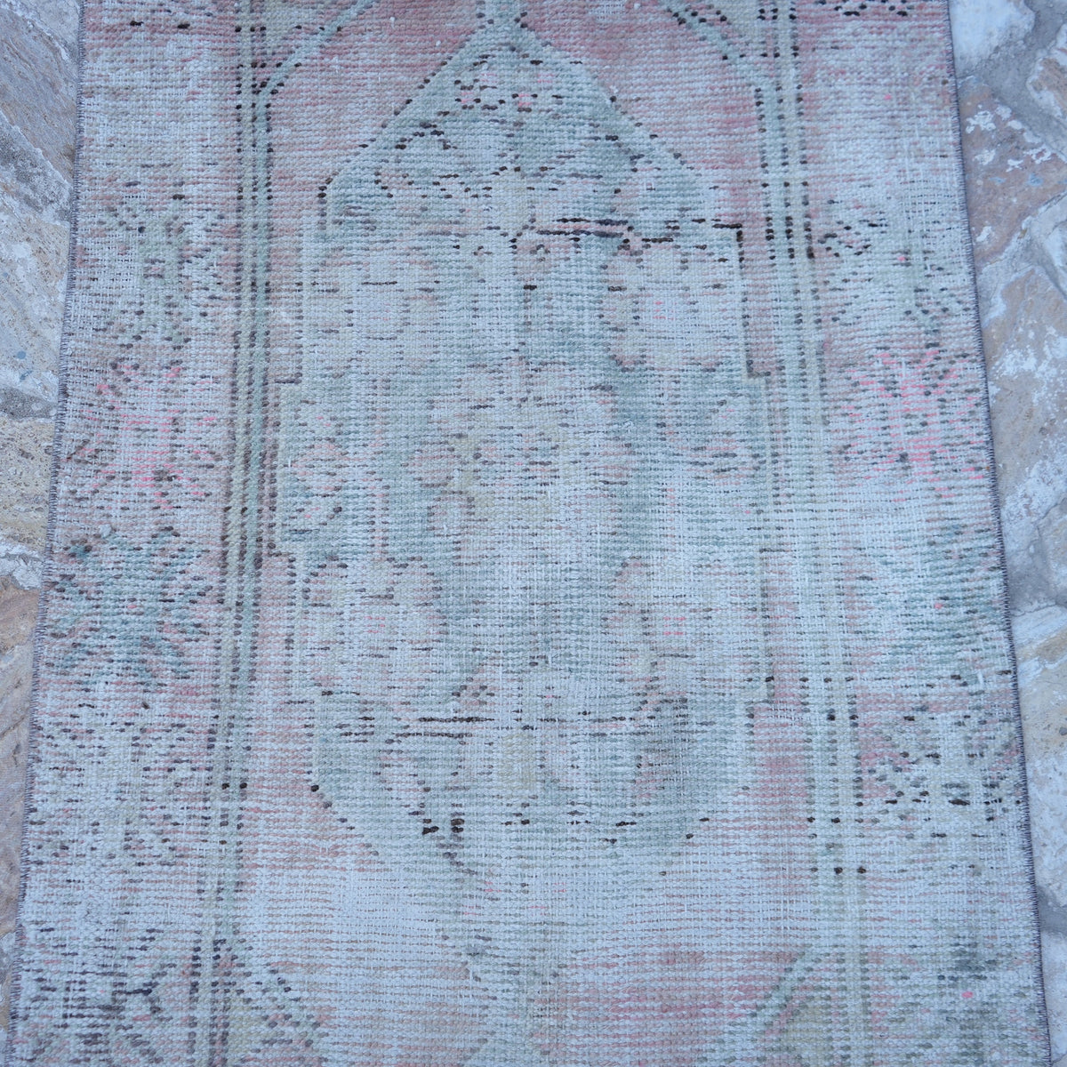 Close-up of the pink Turkish distressed vintage rug showing traditional details, hand-knotted weave, wool and cotton and low pile.