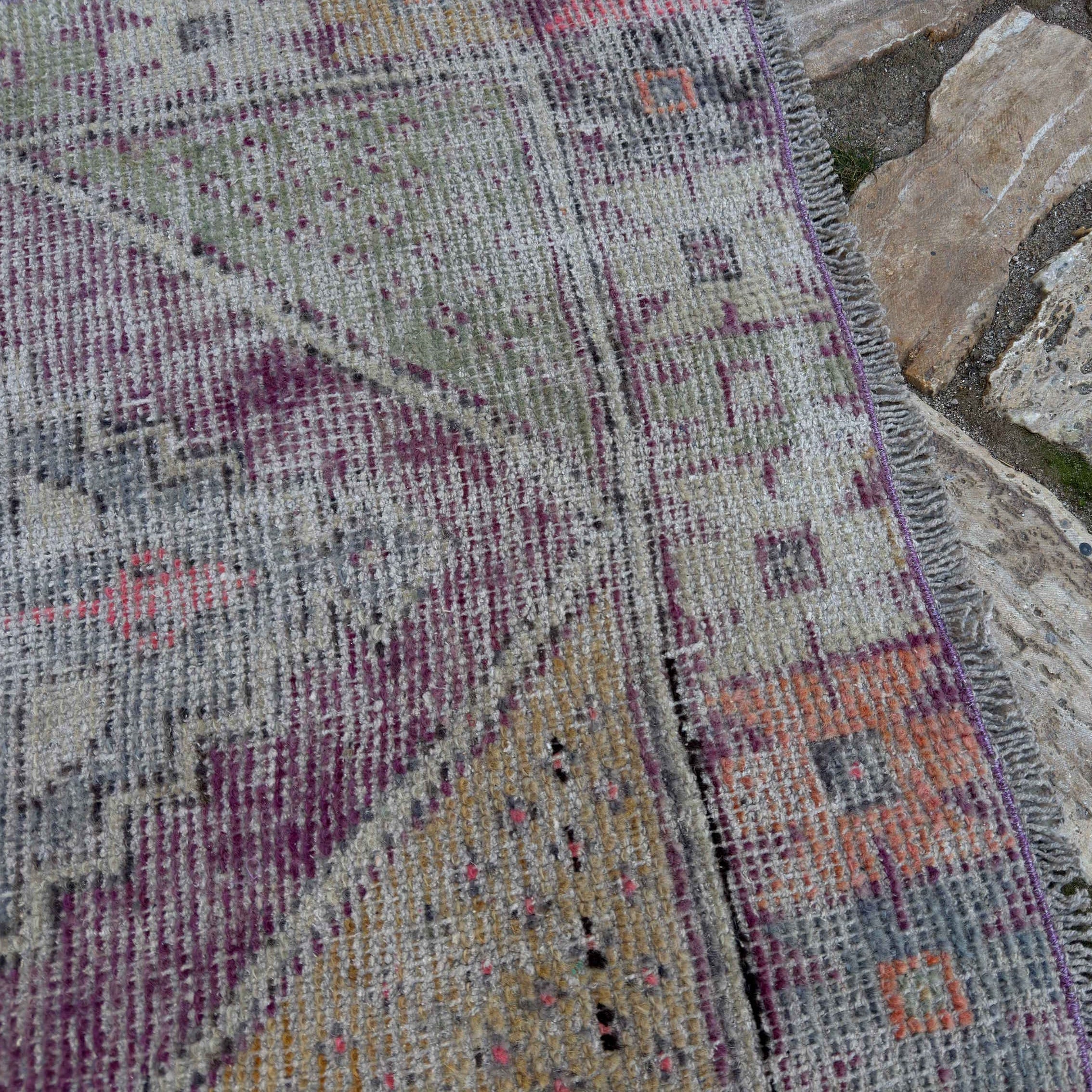 Close-up of the pale purple Turkish distressed vintage rug showing traditional details, hand-knotted weave, wool and cotton and low pile.