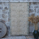 Beige 4' x 6' distressed vintage rug with floral design, handmade in Turkey – Estel.