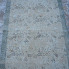Close-up of the beige Turkish distressed vintage rug showing floral details, hand-knotted weave, wool and cotton and low pile.