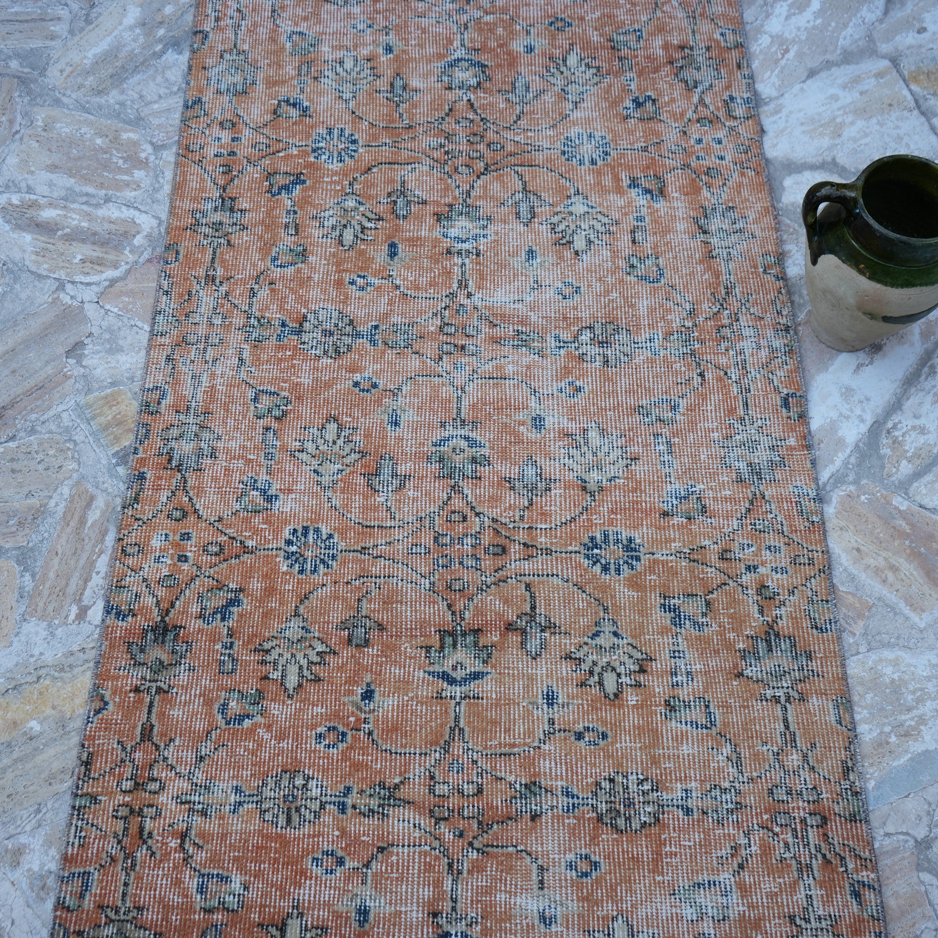 Close-up of the orange Turkish floral runner rug showing floral details, hand-knotted weave, wool and cotton and low pile.