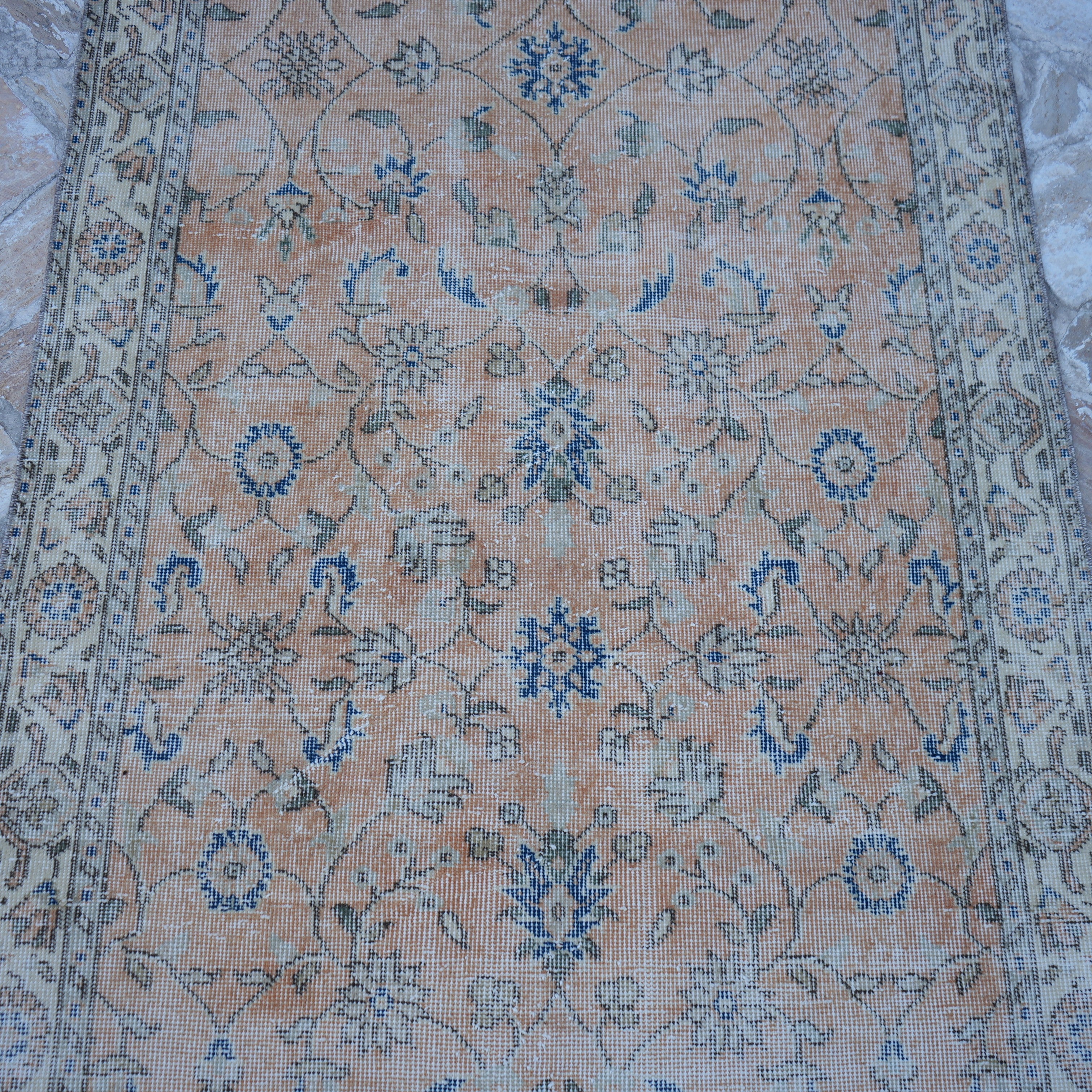 Close-up of the orange Turkish floral vintage rug showing floral details, hand-knotted weave, wool and cotton and low pile.
