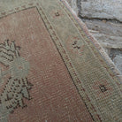 Close-up of the pale red Turkish geometric runner rug showing medallion details, hand-knotted weave, wool and cotton and low pile.