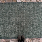 1970s green geometric turkish rug with floral design, hand-knotted weave and low pile.