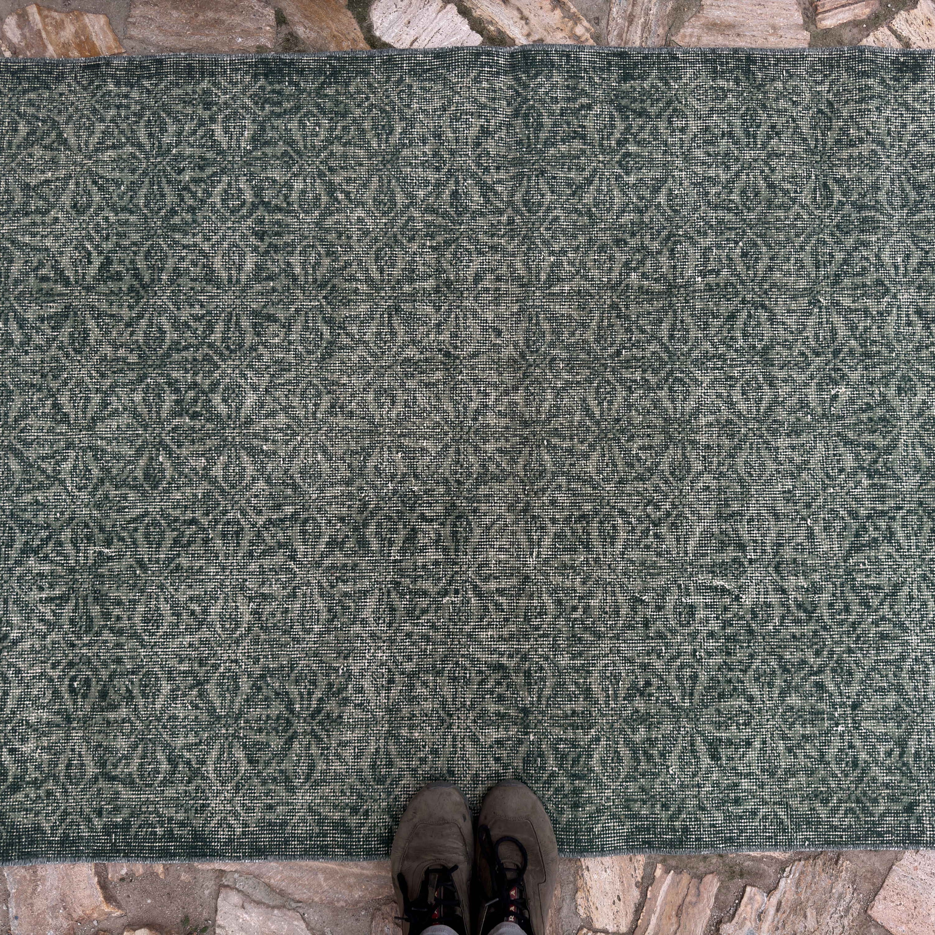 1970s green geometric turkish rug with floral design, hand-knotted weave and low pile.
