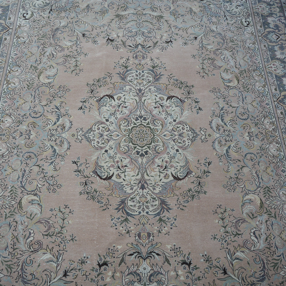 Close-up of the pink hand-knotted persian rug showing medallion details, hand-knotted weave, wool and cotton and low pile.
