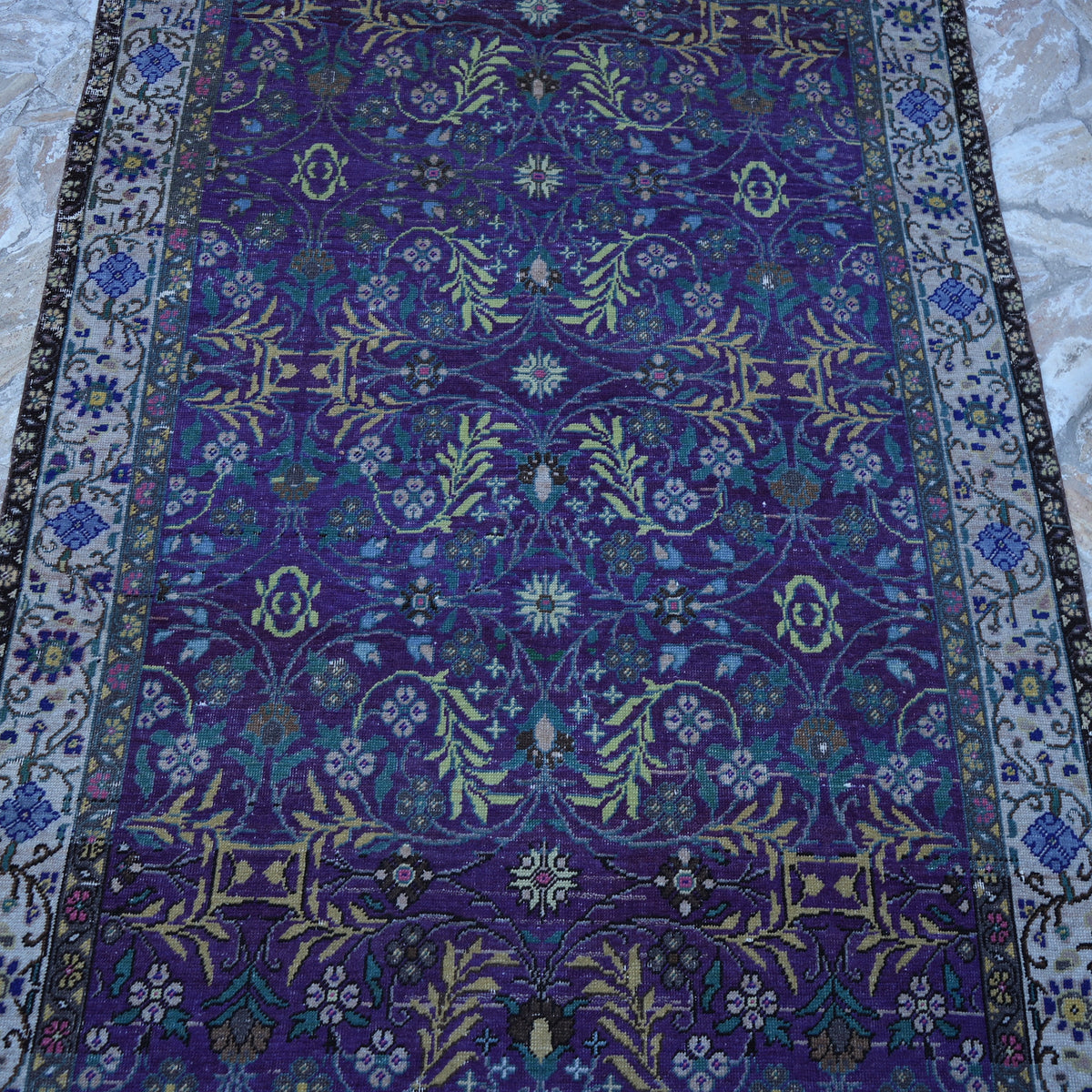 Close-up of the purple Turkish handknotted floral rug showing floral details, hand-knotted weave, wool and cotton and low pile.