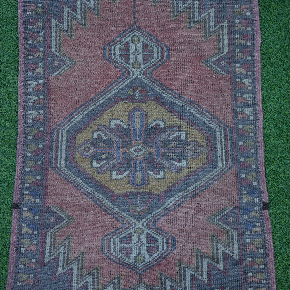 Close-up of the light red Turkish handknotted rug showing traditional details, hand-knotted weave, wool and cotton and low pile.