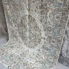 Green 5' x 9' Turkish handknotted rug in wool and cotton, shown on the floor.
