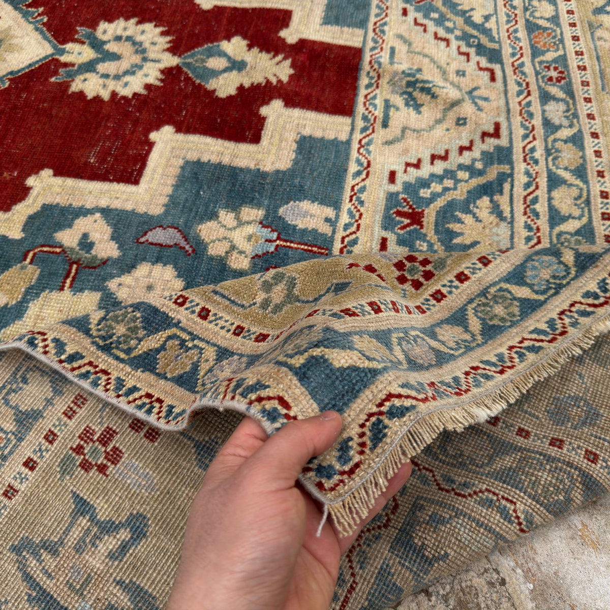 Close-up of the red Turkish handmade traditinoal rug showing traditional details, hand-knotted weave, wool and low pile.