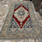 Red 6' x 11' Turkish handmade traditinoal rug in wool, shown on the floor.