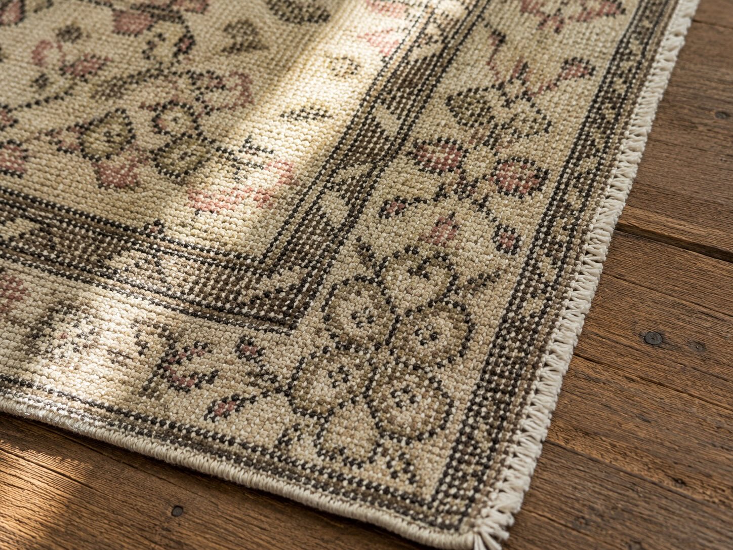 Macro view of hand-tied fringe and knot detail on a vintage handwoven brown and cream rug