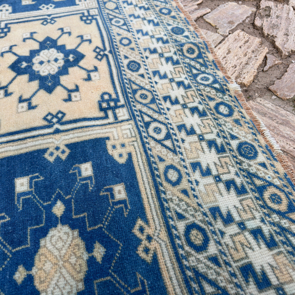 Close-up of the blue large turkish rug showing geometric details, hand-knotted weave, wool and cotton and low pile.