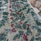 Close-up of the green large turkish rug showing floral details, hand-knotted weave, wool and cotton and low pile.