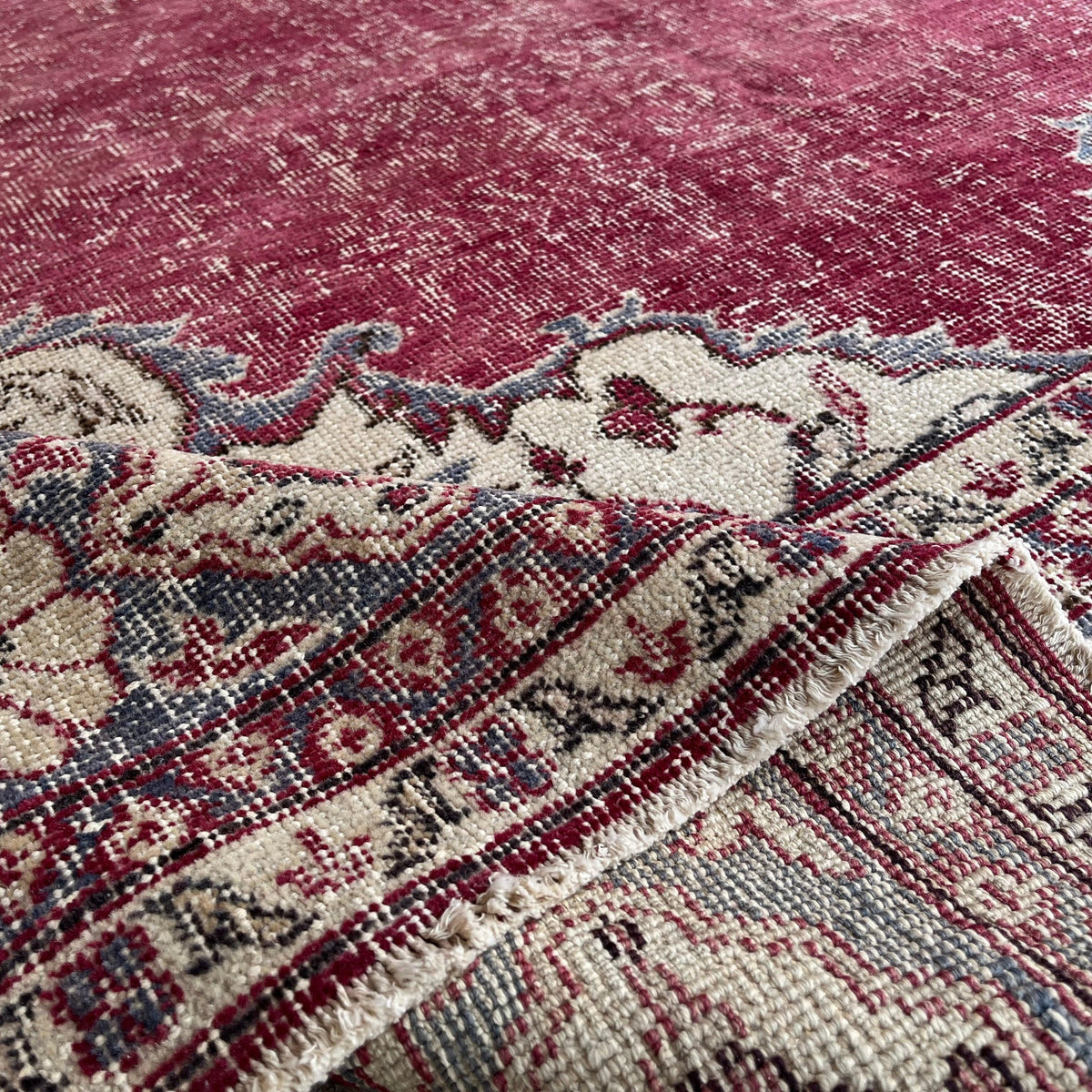 Close-up of the red large turkish rug showing medallion details, hand-knotted weave, wool and cotton and low pile.