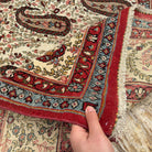 Close-up of the beige large vintage persian rug showing floral details, hand-knotted weave, wool and cotton and low pile.