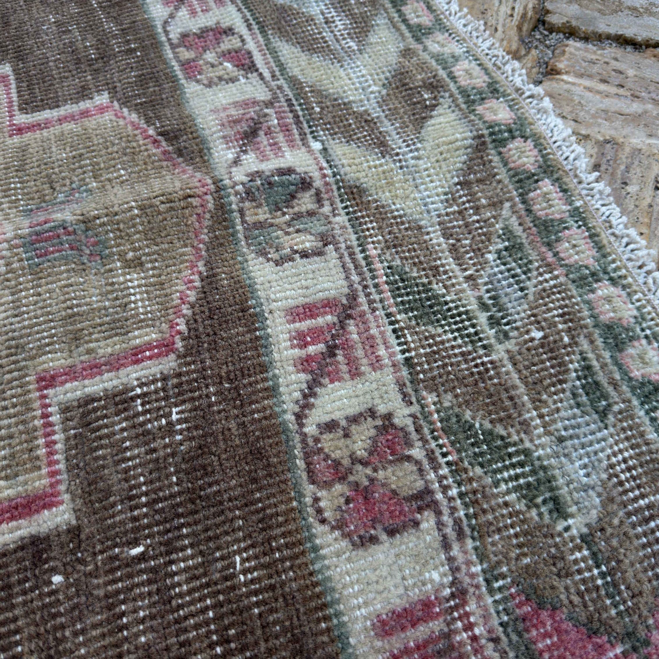 Close-up of the pale pink Turkish large vintage rug showing traditional details, hand-knotted weave, wool and cotton and low pile.