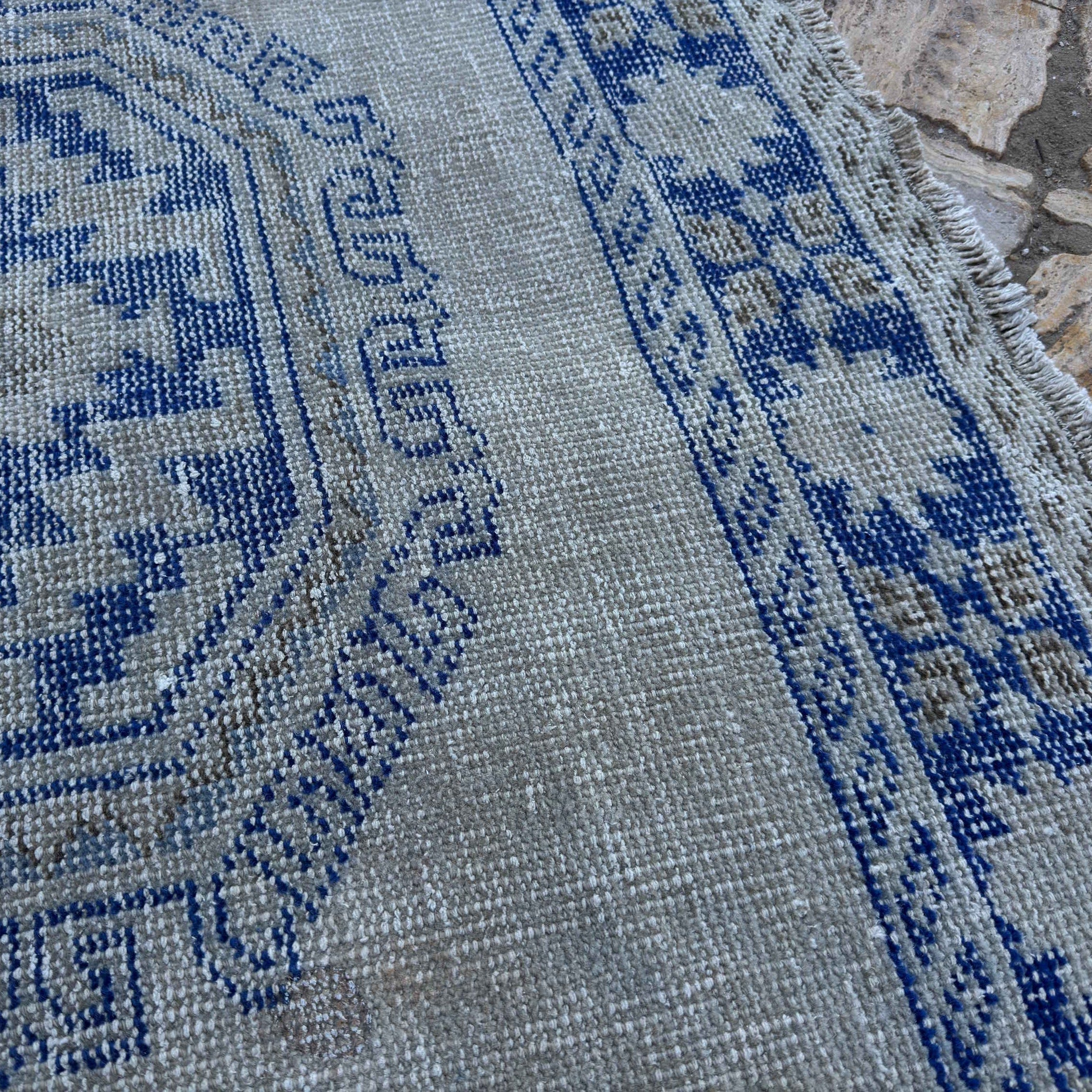 Close-up of the blue Turkish large vintage rug showing neutral details, hand-knotted weave, wool and cotton and low pile.