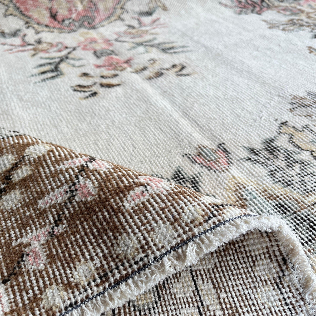 Close-up of the pink Turkish large vintage rug showing medallion details, hand-knotted weave, wool and cotton and low pile.
