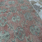 Close-up of the pink large vintage turkish rug showing floral details, hand-knotted weave, wool and cotton and low pile.