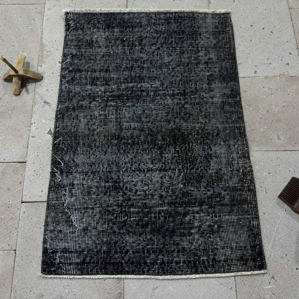 Black 2' x 3' Turkish mini overdyed rug in wool and cotton, shown on the floor.