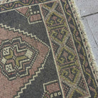 Close-up of the pink Turkish mini runner vintage rug showing traditional details, hand-knotted weave, wool and cotton and low pile.