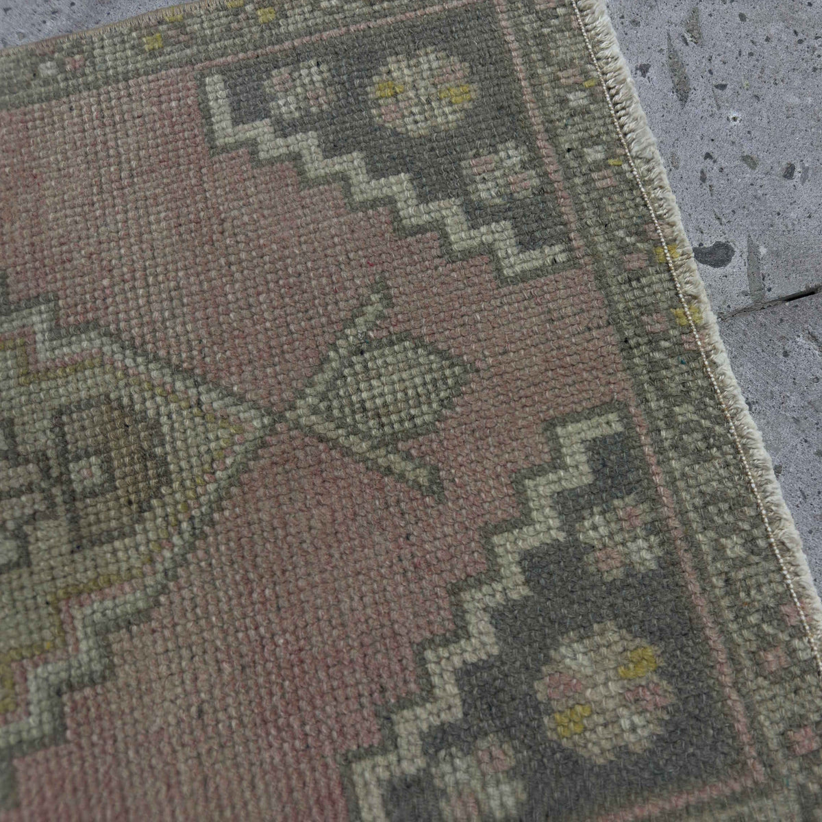 Close-up of the pink Turkish mini vintage rug showing medallion details, hand-knotted weave, wool and cotton and low pile.