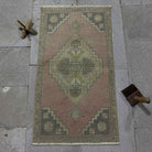Pink 1' x 3' Turkish mini vintage rug in wool and cotton, shown on the floor.