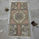 Pink 2' x 3' Turkish mini vintage rug in wool and cotton, shown on the floor.