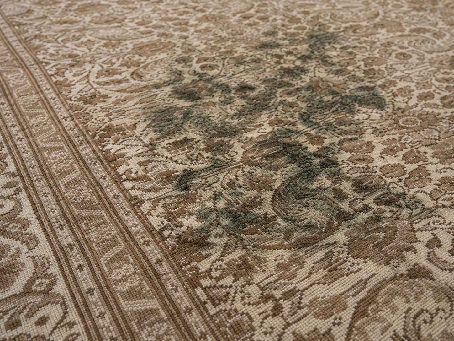 Close-up of green and black mold stains on the pile of a vintage Turkish rug