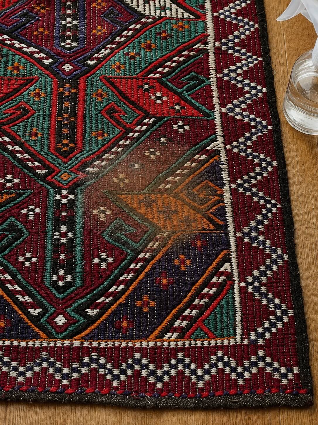 Close-up of a dried coffee stain being rehydrated with water on a vintage kilim rug