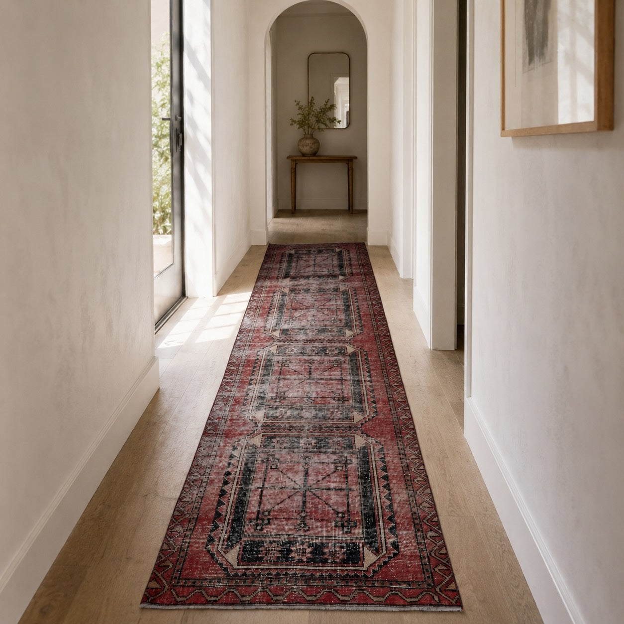 Red and black vintage Turkish runner rug with geometric medallions laid down a bright modern hallway
