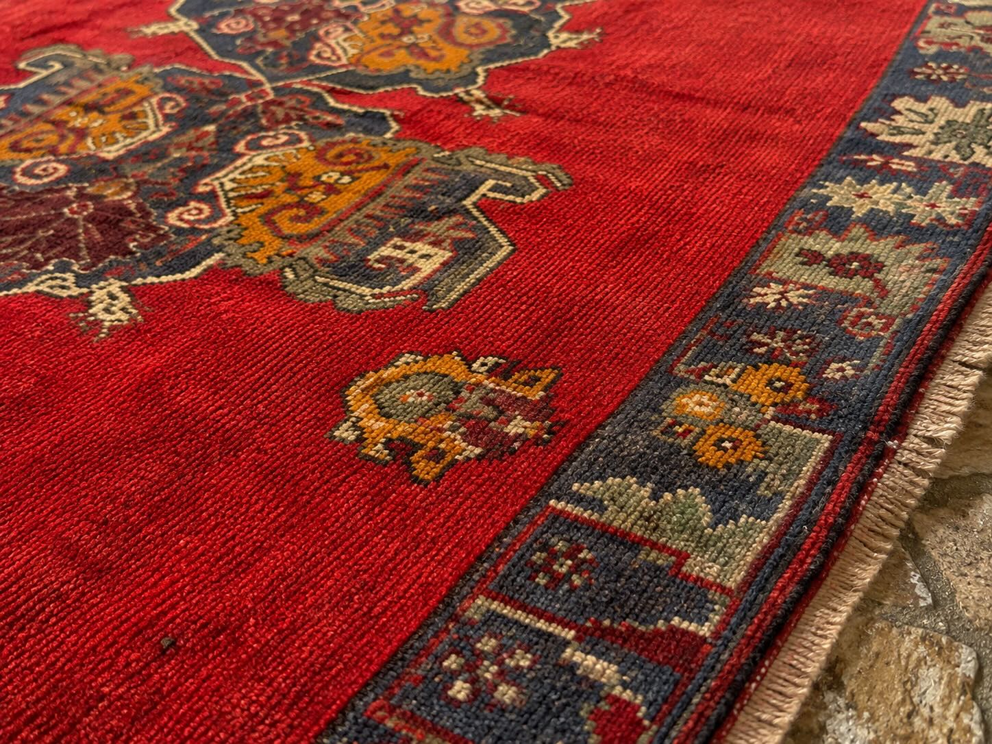 Macro close-up of a red hand-knotted wool rug showing dense pile texture and natural dye color variation