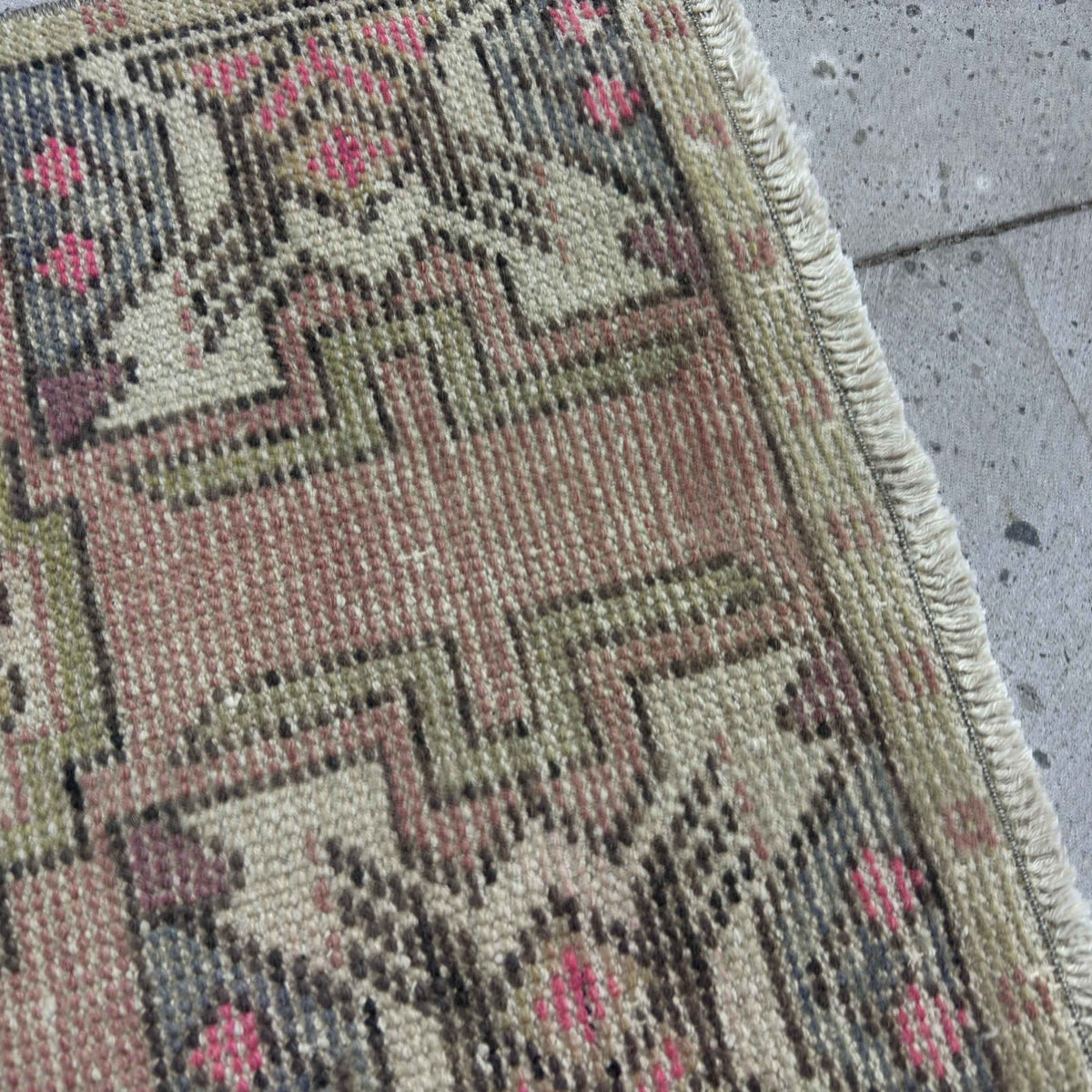 Close-up of the pink Turkish small anatolian rug showing traditional details, hand-knotted weave, wool and cotton and low pile.