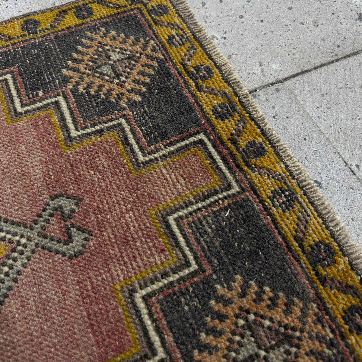 Close-up of the red Turkish small anatolian rug showing traditional details, hand-knotted weave, wool and cotton and low pile.
