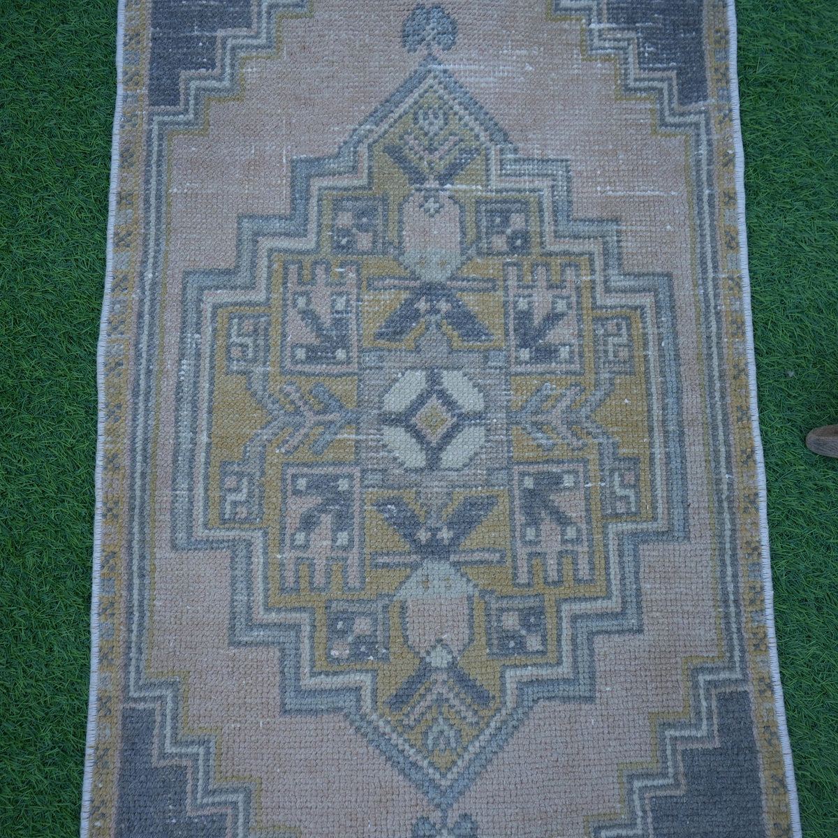 Close-up of the pink Turkish small anatolian rug showing traditional details, hand-knotted weave, wool and cotton and low pile.