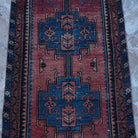 Close-up of the red small persian rug showing traditional details, hand-knotted weave, wool and cotton and low pile.