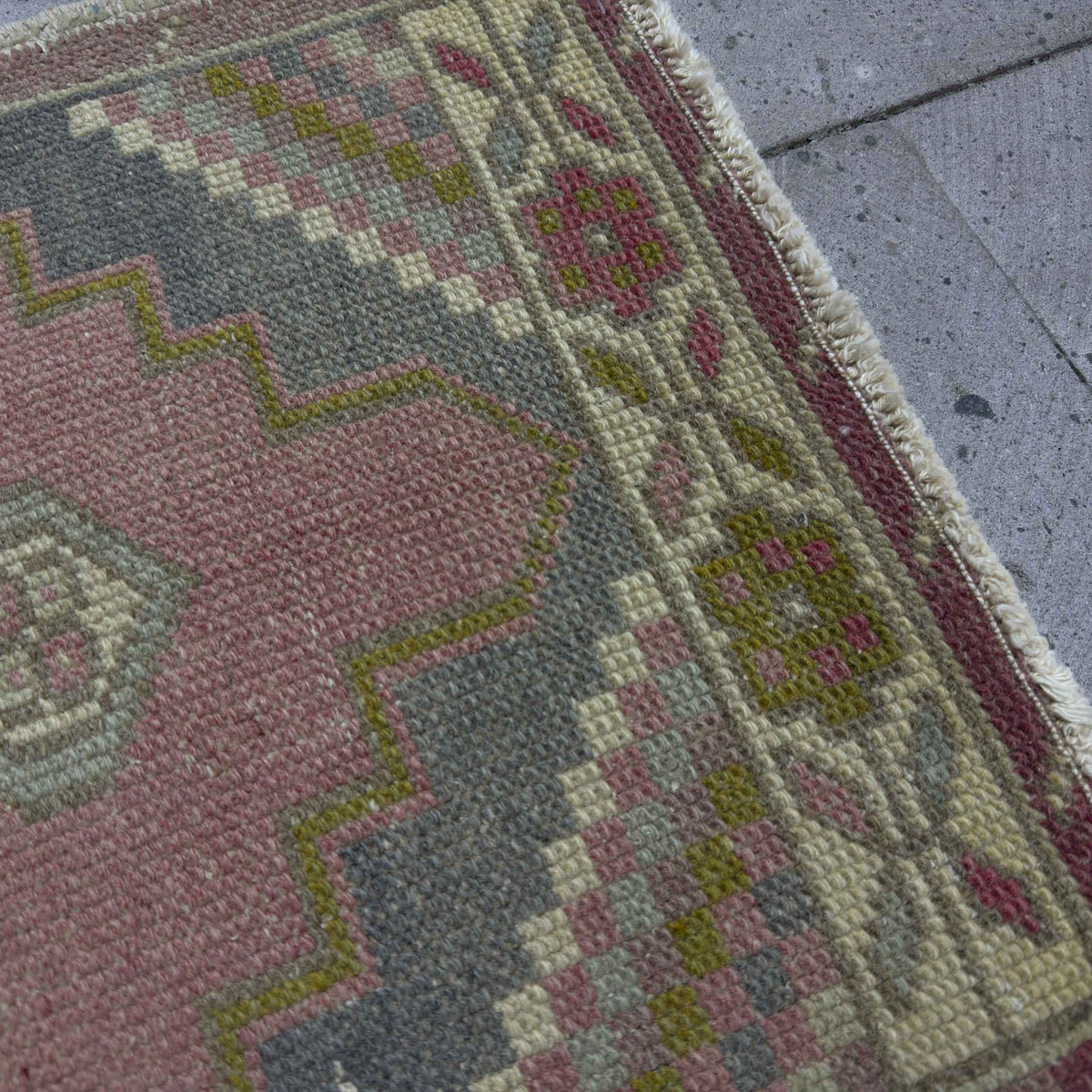 Close-up of the pink small turkish rug showing traditional details, hand-knotted weave, wool and cotton and low pile.