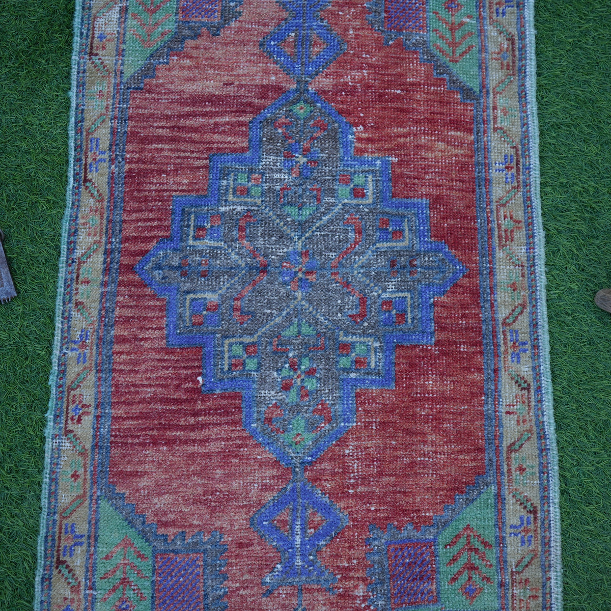 Close-up of the red small turkish rug showing traditional details, hand-knotted weave, wool and cotton and low pile.