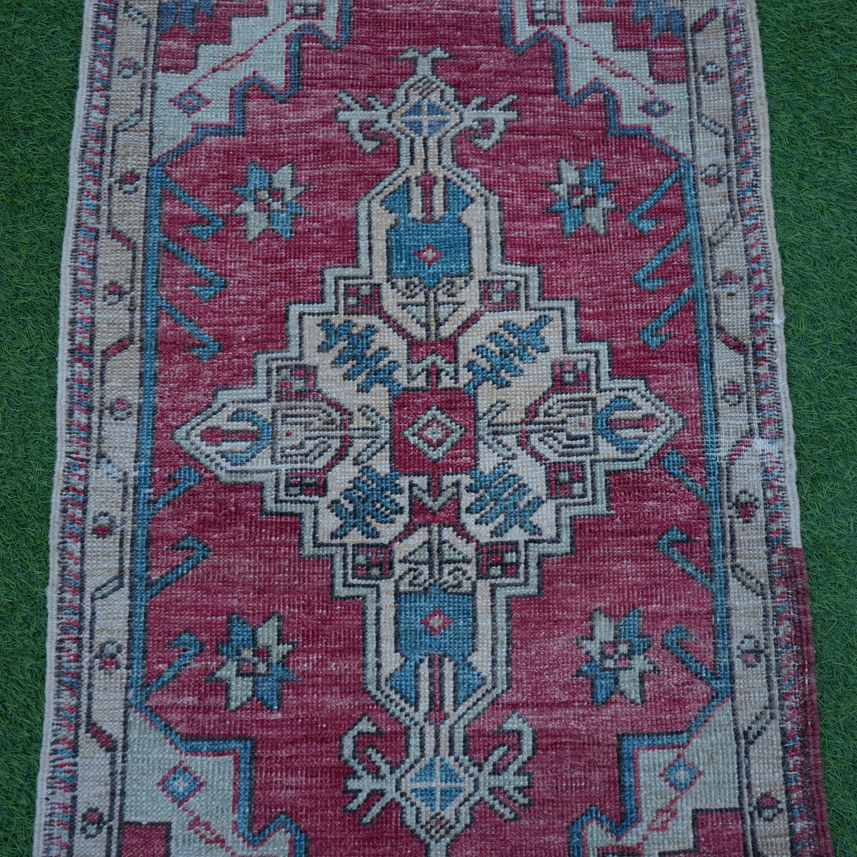 Close-up of the red small turkish rug showing traditional details, hand-knotted weave, wool and cotton and low pile.