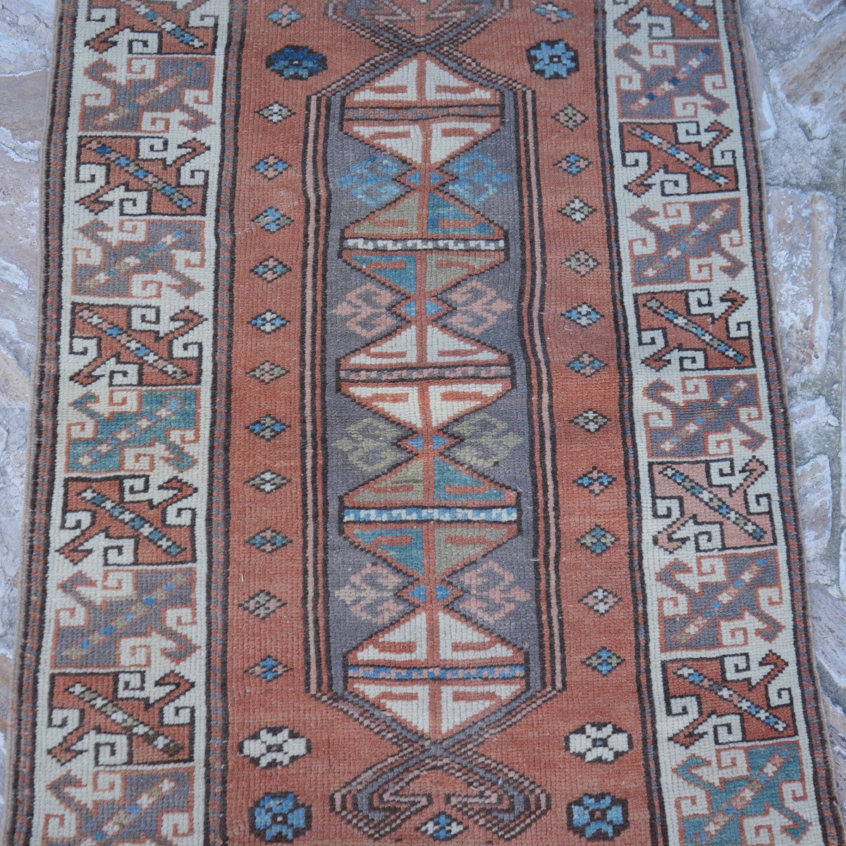 Close-up of the pale orange small turkish rug showing traditional details, hand-knotted weave, wool and low pile.