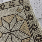 Close-up of the beige Turkish small vintage geometric rug showing neutral details, hand-knotted weave, wool and cotton and low pile.