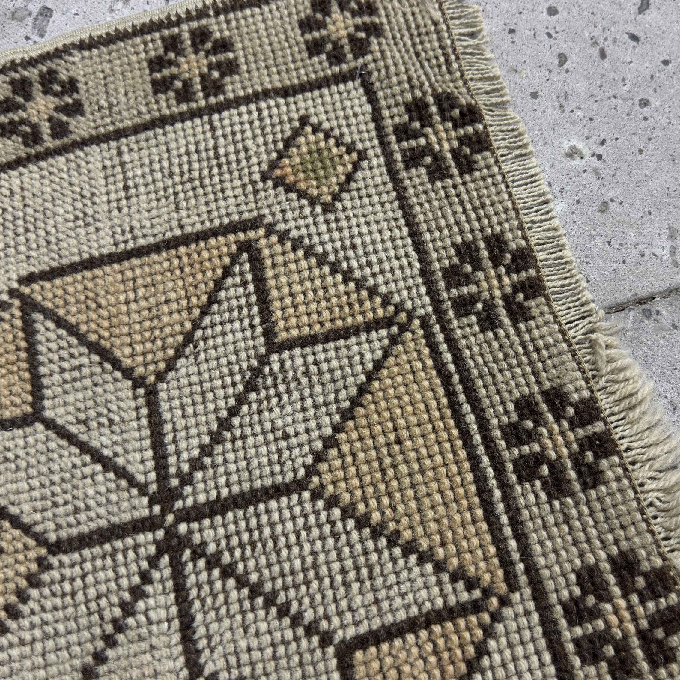 Close-up of the beige Turkish small vintage geometric rug showing neutral details, hand-knotted weave, wool and cotton and low pile.