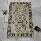 Beige 2' x 3' Turkish small vintage geometric rug in wool and cotton, shown on the floor.