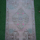 Close-up of the pink Turkish small vintage rug showing traditional details, hand-knotted weave, wool and cotton and low pile.