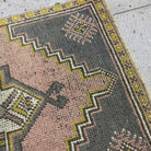 Close-up of the pink Turkish small vintage rug showing traditional details, hand-knotted weave, wool and cotton and low pile.