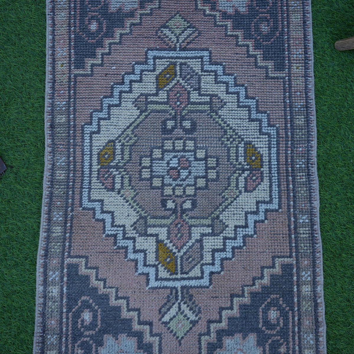 Close-up of the pink Turkish small vintage rug showing traditional details, hand-knotted weave, wool and cotton and low pile.
