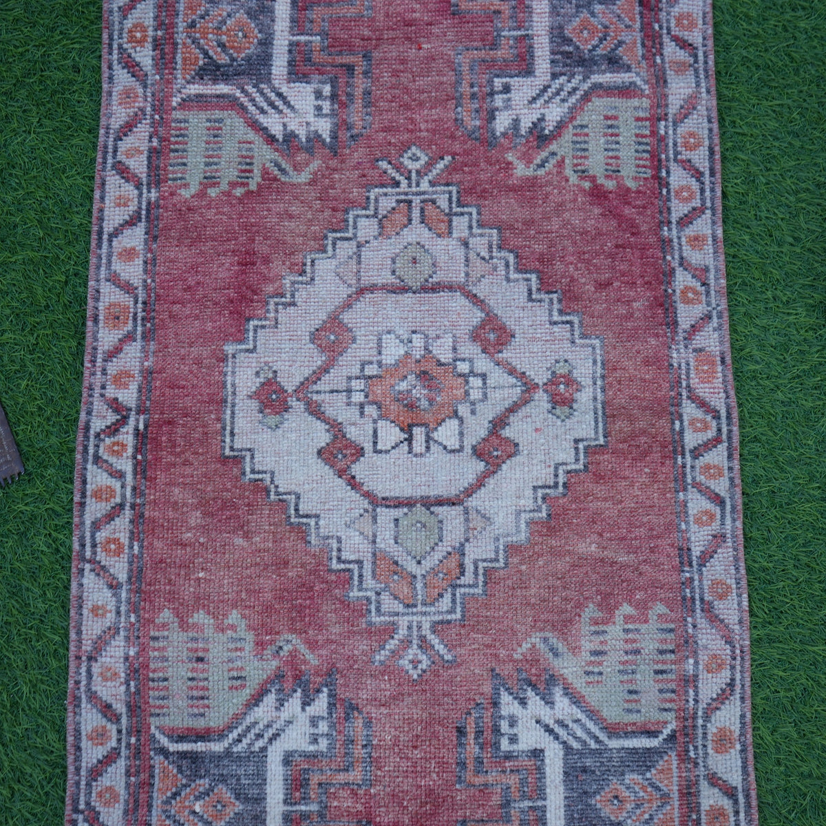 Close-up of the red Turkish small vintage rug showing traditional details, hand-knotted weave, wool and cotton and low pile.